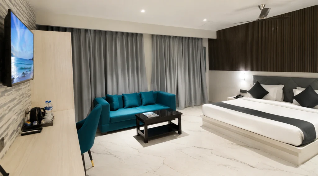 Hotel room with a white bed and blue sofa at Hotel Sankalp Banaras